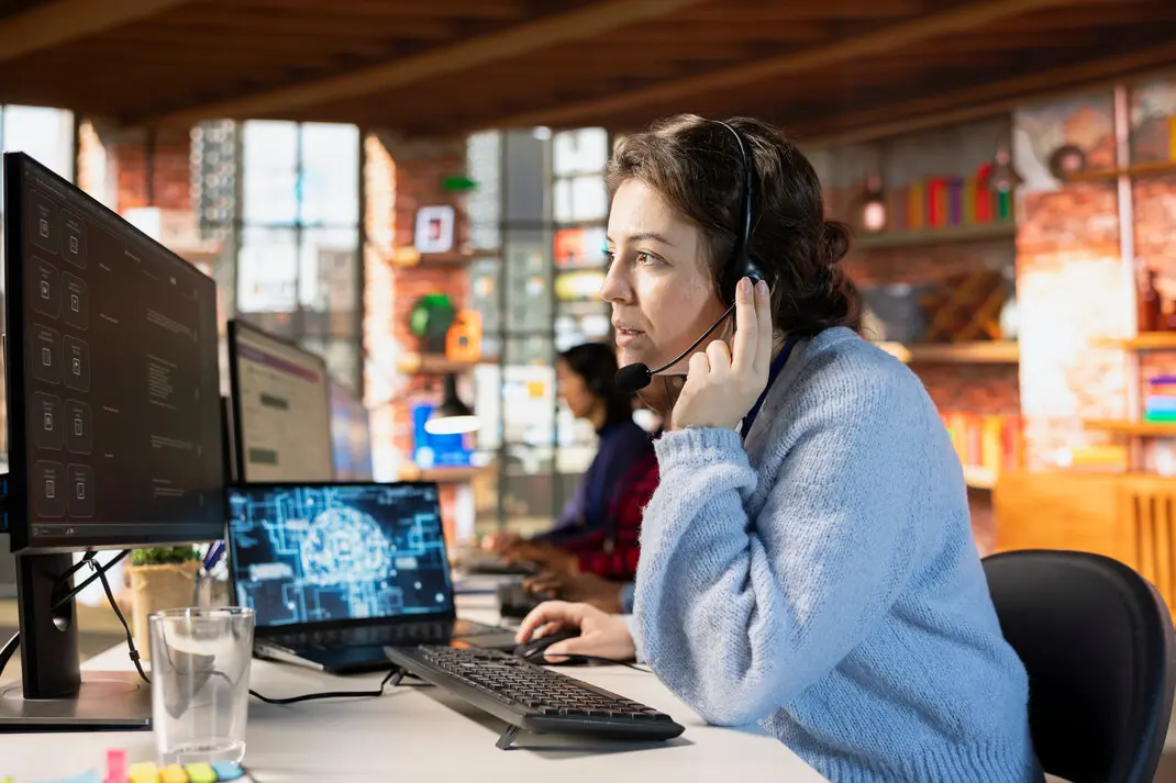 Support engineer working across two screens in an open office